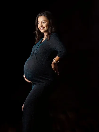 A low-key portrait where the light gently illuminates the mother's smile and baby bump. This technique creates a very intimate and serene feeling.