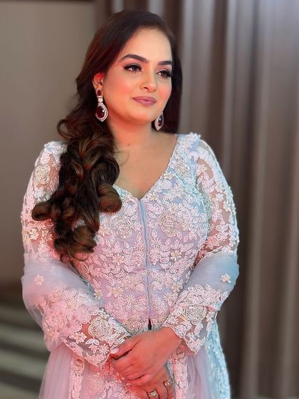 The complete look, showing how the soft makeup complements her intricately embroidered pastel blue outfit. It's a perfect example of understated elegance.