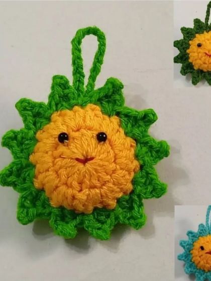 This crochet sun charm features a happy face and a loop for hanging. It's great as a car mirror decoration, a bag charm, or even a festive ornament.