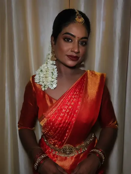 A beautiful portrait of a dusky bride. The makeup is flawless, with a matte finish that looks stunning against her traditional red saree.