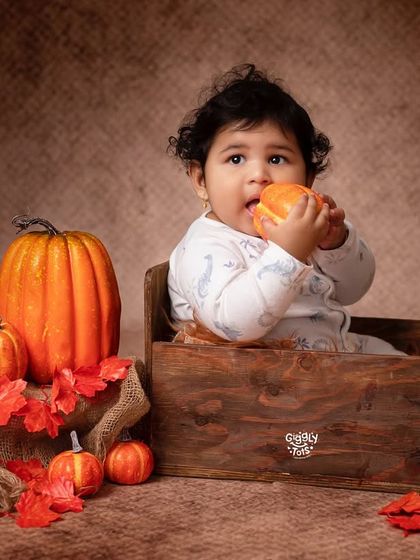 Pumpkin kisses and harvest wishes. A sweet baby enjoys a little pumpkin snack during our autumn-themed shoot.