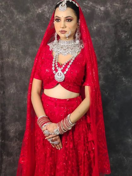 A full view of the bride in the red lehenga with the heavy, multi-layered American Diamond set. A showstopper look for a grand reception.