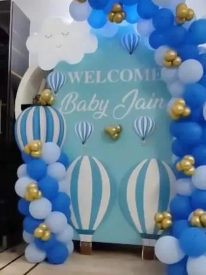 A "Welcome Baby Jain" backdrop with a hot air balloon theme. The blue and white balloon arch creates a dreamy and sweet setup for the new arrival.