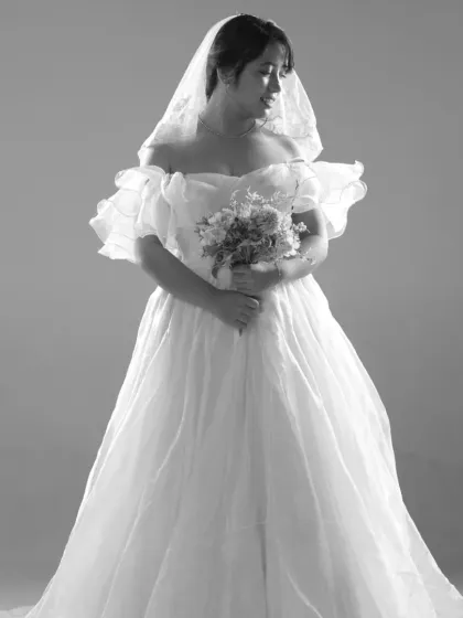 A beautiful black and white portrait showcasing the delicate ruffled sleeves and full skirt of our white organza ball gown. This dress is timelessly elegant.