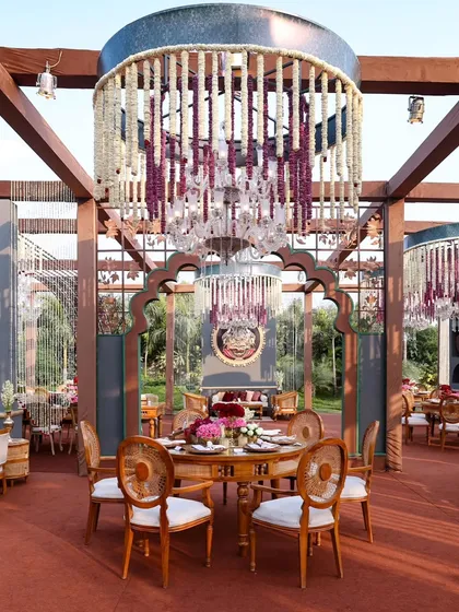 A stunning dining setup under a custom-built pergola. The massive floral chandeliers, a signature of my designs, add a sense of grandeur and romance to the guest dining experience.
