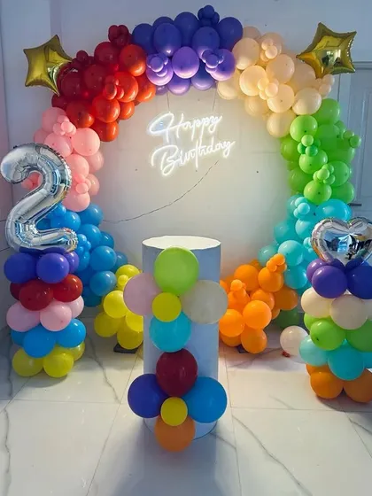 A vibrant rainbow-colored balloon arch for a 2nd birthday. This cheerful setup is perfect for a fun and colorful party.