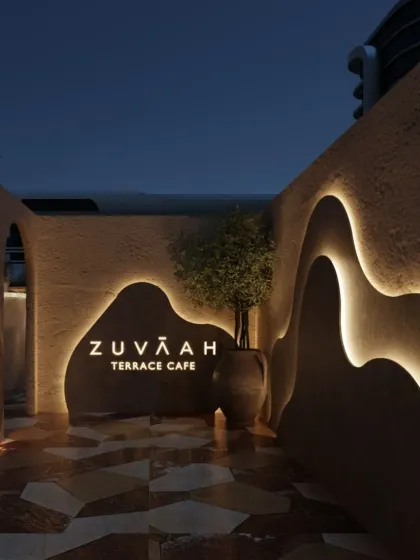 The entrance to Zuvaah's terrace café features organic, curving walls with integrated lighting, guiding guests into the space. The design immediately establishes a moody, Mediterranean-inspired atmosphere.