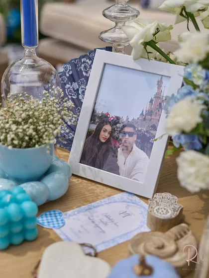 A close-up of a table, showing a framed photo of the couple, custom stationery, and other small, personalized decor items.