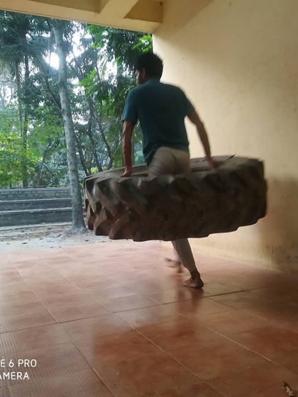 A student carries the tire, demonstrating raw strength and determination.