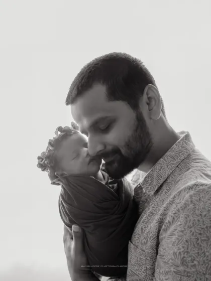 A father's love is a quiet strength. This black and white portrait focuses on the gentle, protective embrace of a dad holding his newborn for the first time.