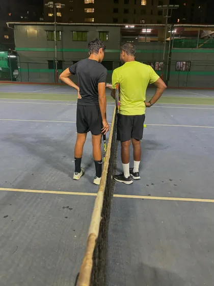 A back view of a coaching moment at the net. We analyze every aspect of a player's game to identify areas for improvement.