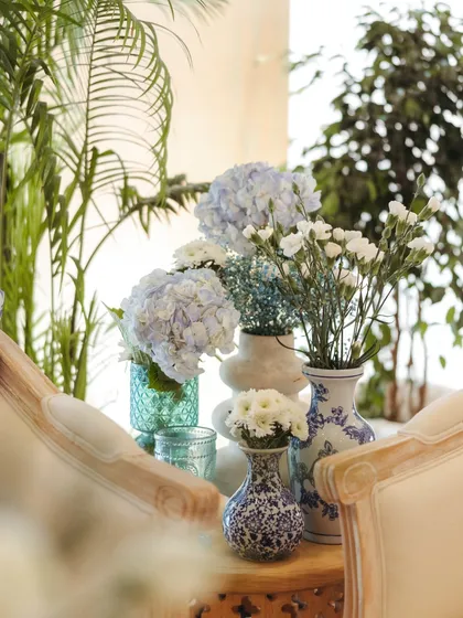 A cozy corner with blue and white chinoiserie vases holding simple floral arrangements, demonstrating how theme can be carried through even the smallest details.
