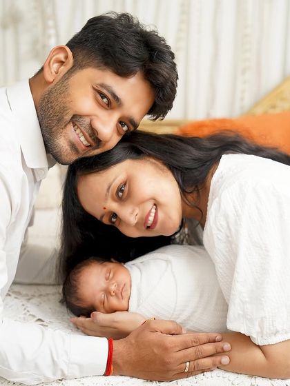A creative and loving family pose. The parents lie on either side of their sleeping baby, creating a sweet and symmetrical portrait of their new family.