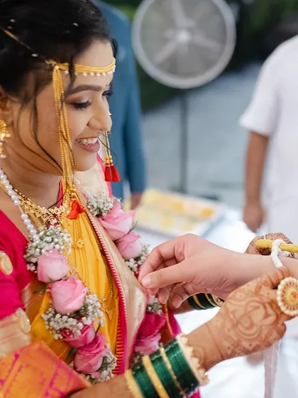 A close-up of a wedding ritual, highlighting the bride's beautiful mehndi and traditional green bangles.