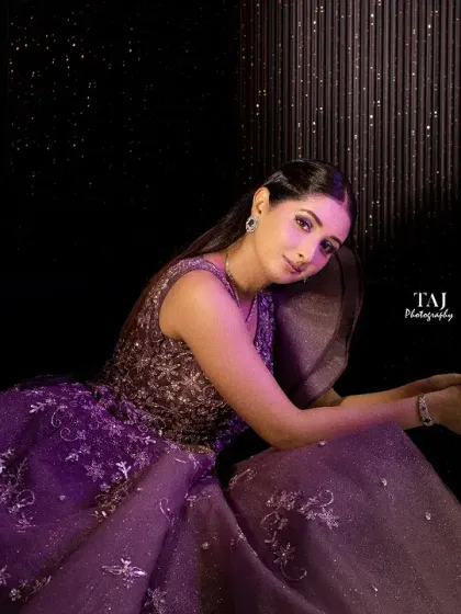 A glamorous and moody solo portrait of the bride. The dark background and dramatic lighting highlight her sparkling purple gown and confident pose.