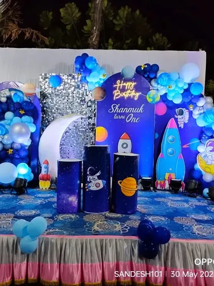 An out-of-this-world outer space themed birthday party. The stage is decorated with astronaut and rocket cutouts, planet-themed props, and a galaxy backdrop.