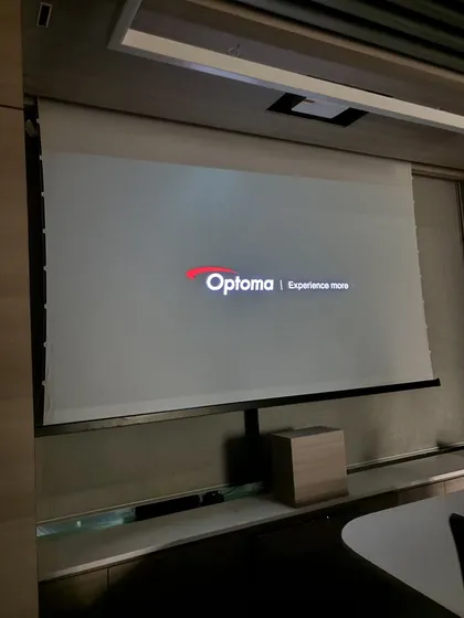 My work also extends to corporate and commercial spaces. Here is a seamless installation of an Optoma ultra-short-throw projector with a 120-inch ALR screen in a modern conference room, designed for high-impact presentations.