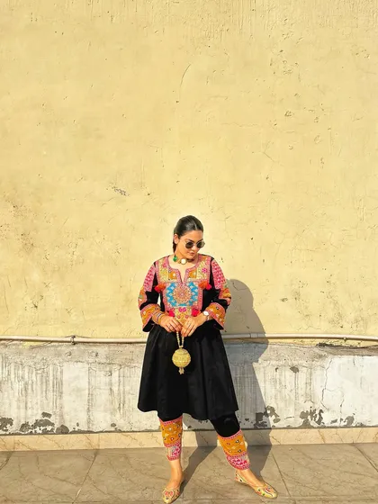 A wider shot to show how the golden potli bag stands out, adding a point of light and luxury to the overall traditional ensemble.