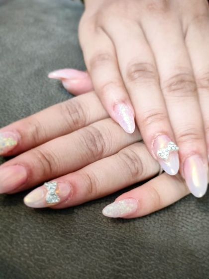 A video showing off a pearly, iridescent manicure with sparkling silver rhinestone bow charms on the accent nails.