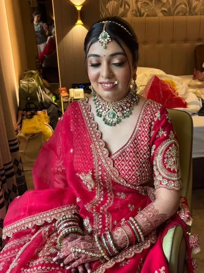 The bride's smile says it all. This look was created to bring out her joy and confidence, with a focus on glowing skin and eyes that sparkle. The pink lehenga and emerald jewelry pair beautifully with the soft glam makeup.