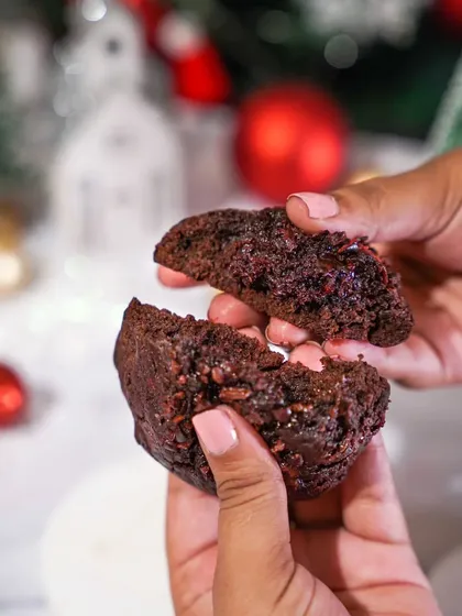 Hands breaking open a gooey, rich chocolate cookie. The close-up on the texture and filling makes this a perfectly tempting shot for a Christmas cookie promotion.