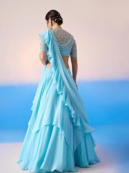 The back of this sky blue lehenga reveals a beautifully embellished blouse and a sheer, ruffled dupatta.