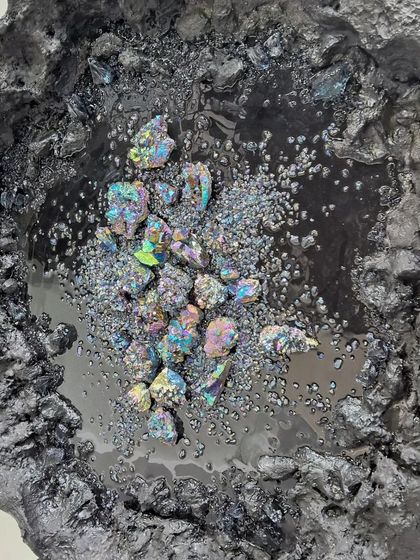 A close-up of a textured artwork by Maria Molaei, resembling a geode with iridescent crystals.