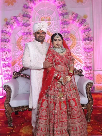 A full-length portrait of the beautiful couple on their wedding stage. The bride's makeup and lehenga look absolutely perfect under the lights.
