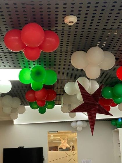 Christmas balloon decorations hanging from the ceiling, using the classic red, green, and white color scheme.