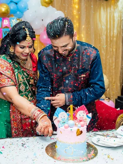 An action shot of the couple cutting their baby shower cake, surrounded by confetti and a happy family member.