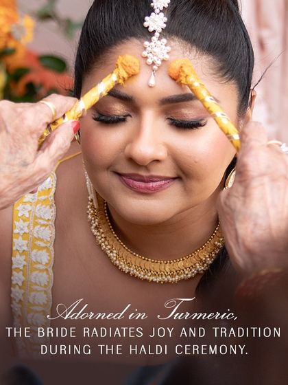 Adorned in turmeric, the bride radiates joy and tradition. This close-up captures the beauty of the ritual and the elegance of her simple, gold-toned jewelry.
