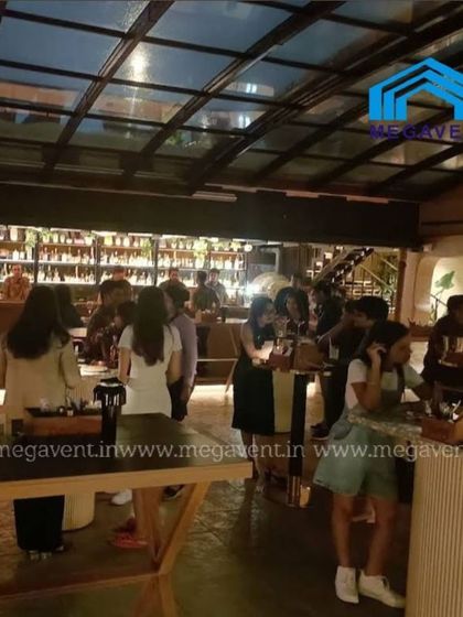 A night view of another retractable roof installation at a busy bar. The transparent roof panels allow guests to enjoy the evening ambiance while staying protected.