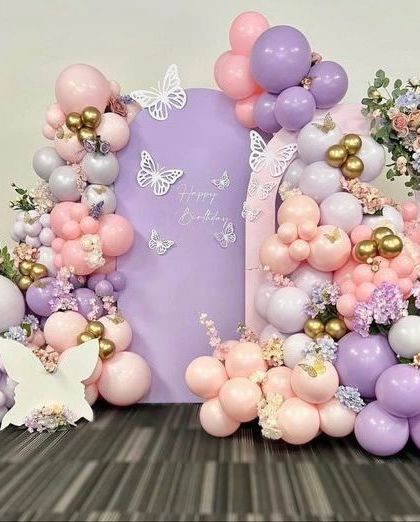 A flutter of color for a happy birthday. This butterfly-themed decor uses a beautiful mix of pink, purple, and gold balloons, combined with fresh flowers, to create a vibrant and cheerful backdrop.