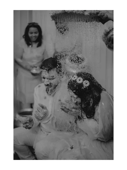 I love capturing moments in classic black and white, even during a colorful Haldi. It strips away distractions and focuses purely on the emotion and action, like this shot of the couple being doused in water.