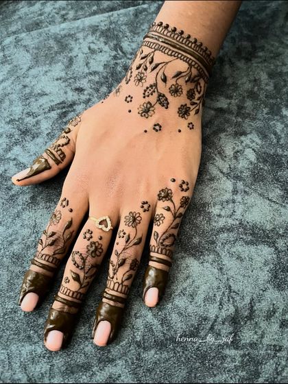 A delicate floral vine design on the back of the hand. The pattern features small flowers and leaves, with solid color on the fingertips.