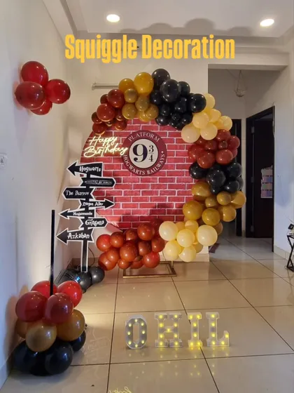 A creative Harry Potter themed photo booth with a Platform 9 3/4 brick backdrop, a circular balloon arch, and a directional sign prop.