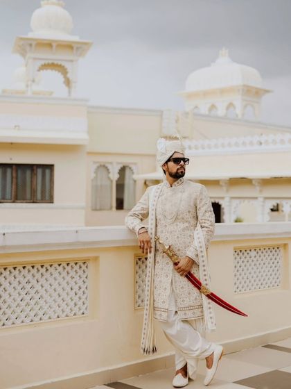 A regal portrait of the groom, Kunal, in his sherwani and holding a traditional sword, looking every bit the royal groom.