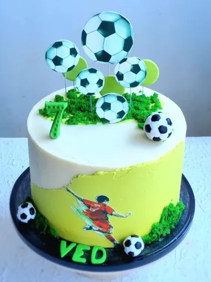 An overhead view of the football-themed cake, showing the arrangement of the toppers on the buttercream grass.