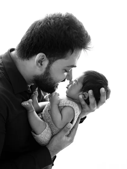 A beautiful black and white portrait of a father and his newborn. The high-contrast lighting creates a powerful and emotional image focused on their connection.