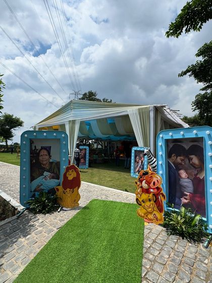 The entrance to the Lion King party featured a walkway lined with large, framed photos of the family, personally welcoming guests. Character cutouts of Simba and Pumbaa were placed alongside to tie into the jungle theme.