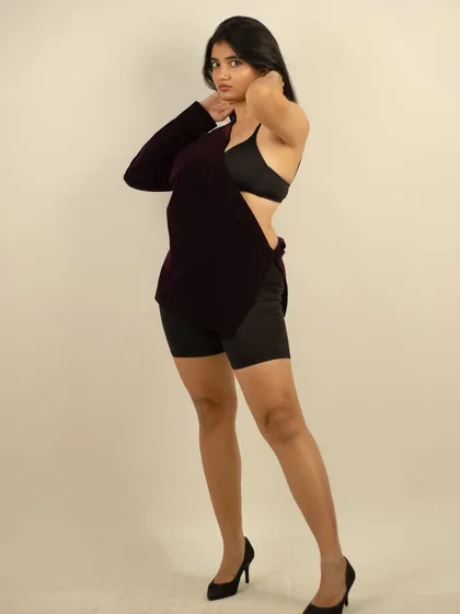 A dynamic standing pose that highlights the asymmetrical design of the velvet garment.