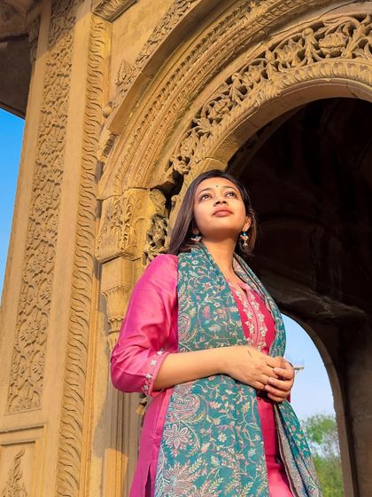 A low-angle shot that highlights the intricate carvings of the palace archway and the beautiful details of my kurti set.