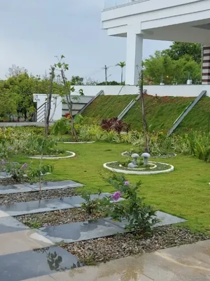 A commercial property landscape featuring a mix of lawn, gravel beds, and paved areas. The sloped lawn area is stabilized with retaining structures.