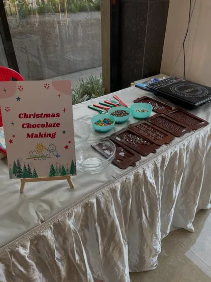 I make parties easy by bringing everything you need. This is a peek at my Christmas chocolate making station, all set up with molds, toppings, and a sign before the little chocolatiers arrive. You just provide the space, I handle the rest.