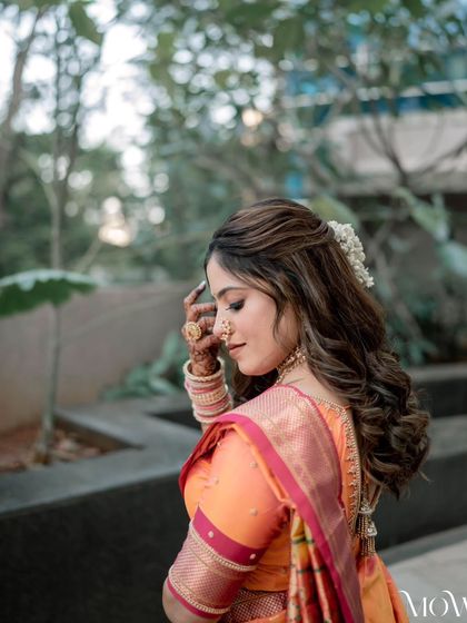 A side profile of the bride, showing her soft curls and the delicate flower in her hair. This is a simple and romantic look.