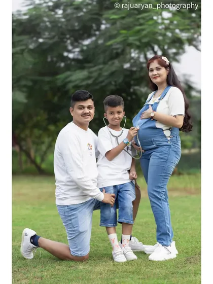 Here’s a creative way to involve older siblings. The big brother plays 'doctor' with a stethoscope on the baby bump, making for a fun and heartwarming family portrait that everyone will cherish.