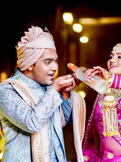 A playful moment where the bride pours a drink for the groom.