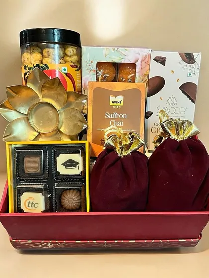 A gourmet Diwali gift tray filled with a variety of treats. This hamper includes artisanal chocolates, saffron chai, roasted cashews, and other delicious snacks in festive packaging.