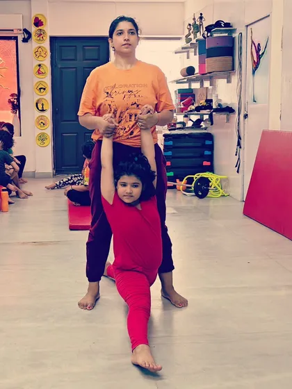 As a mother myself, I understand the importance of a nurturing environment. This is a special moment with my own daughter, helping her with a standing split. I bring this same personal care and encouragement to every child in my studio.