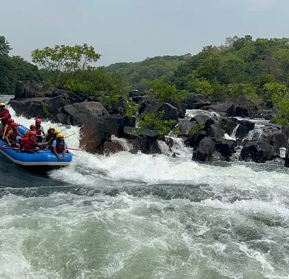 A wide shot of a raft approaching a natural drop on the Kali River. This highlights the stunning and dramatic landscapes you'll encounter during our Dandeli summer camps.